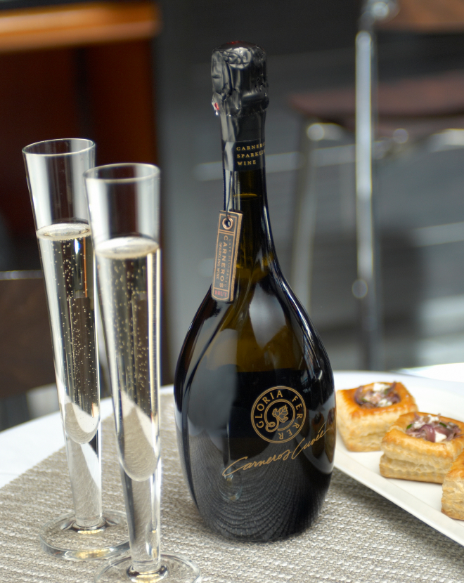 Image of three caviar bites with two flutes with sparkling wine